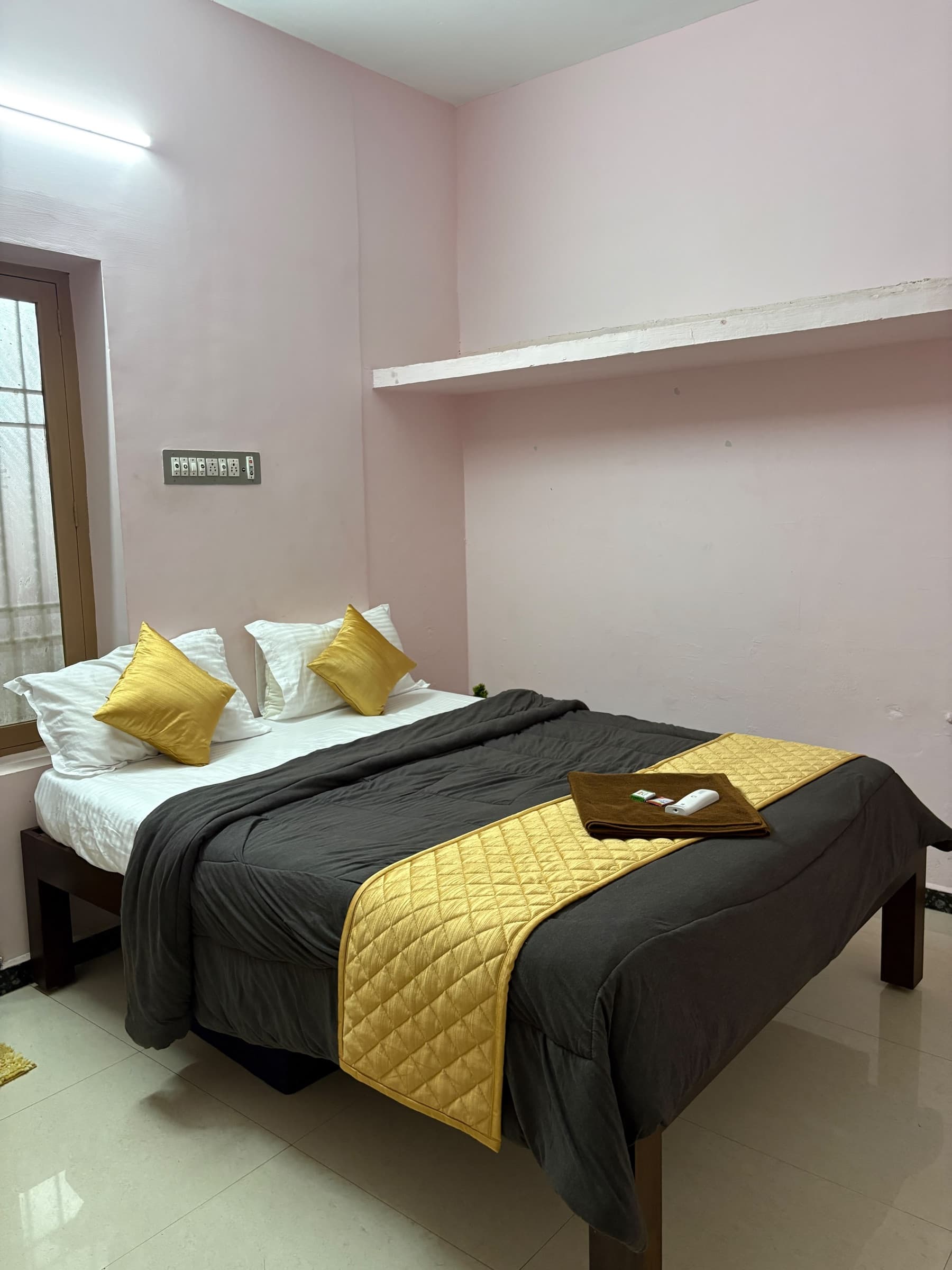 Bedroom with a double bed, white linen and mustard-gold cushions beside the window