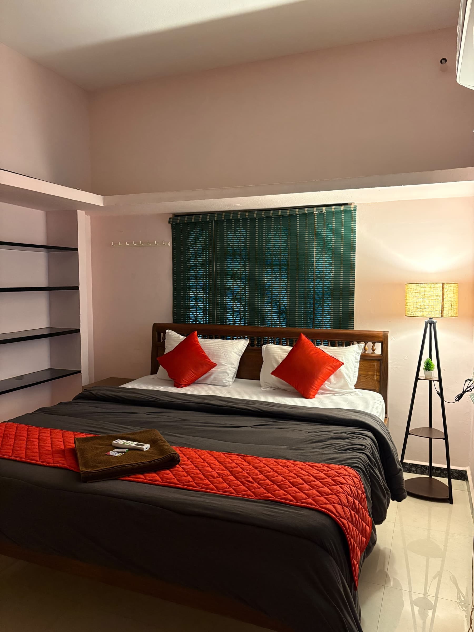 Red-accented bedroom with open wall shelves and a tripod floor lamp