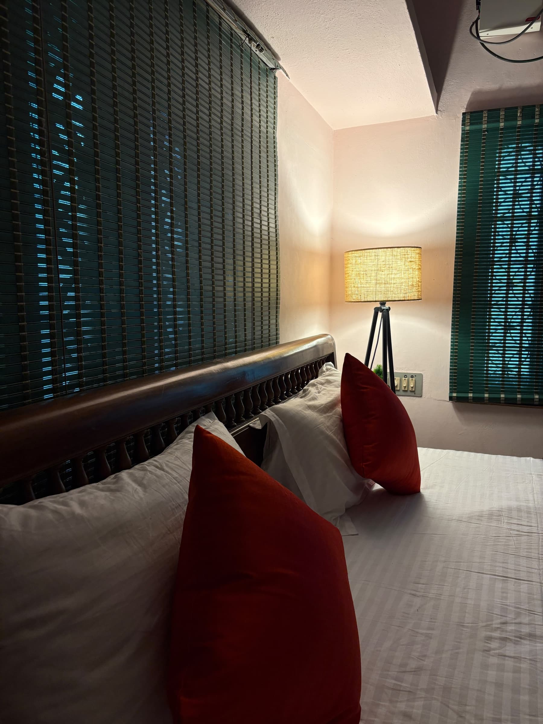 Red cushions and crisp white linen against a dark wooden headboard