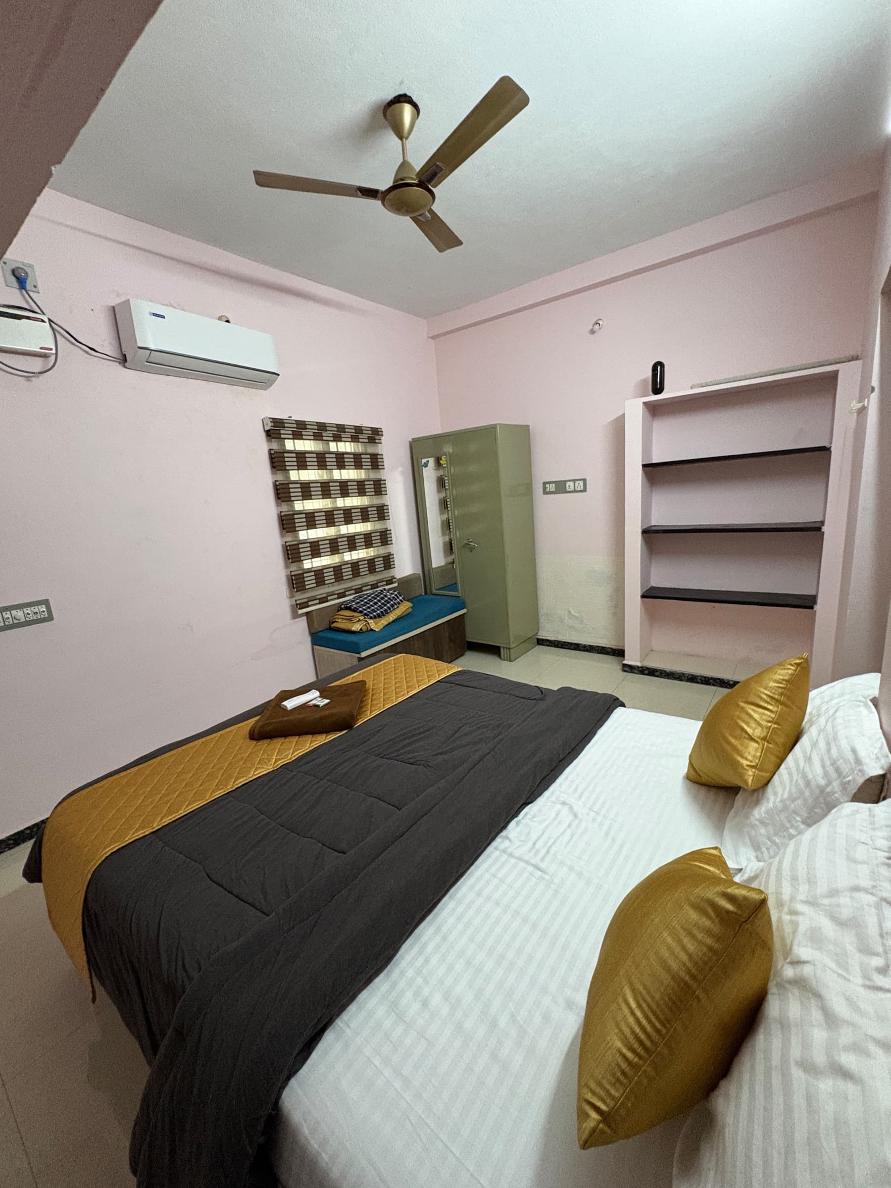 Bedroom with a split air conditioner, a steel wardrobe and open wall shelves